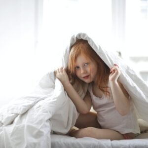 child covering her body in a white comforter
